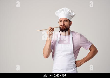 Der professionelle Koch im Vorfeld hält einen Löffel und kocht Essen Stockfoto