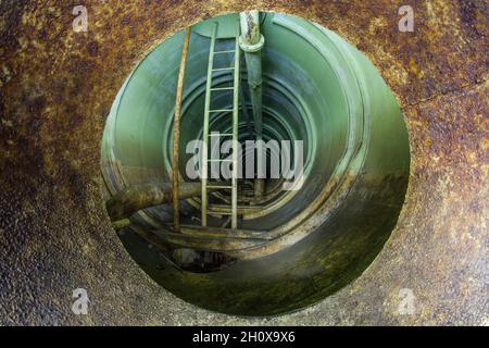 Überreste des unterirdischen Treibstoffdepots der sowjetischen Armee in Rabštejn-Janská, Tschechien. Ein Blick in einen der großen Brennstoffe schleicht durch eine rostige Öffnung. Stockfoto