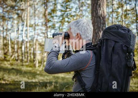 Mann im Wald, Blick durch ein Fernglas Stockfoto