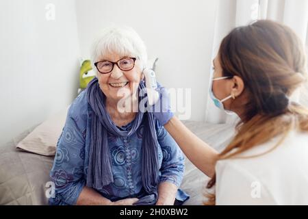 Krankenschwester überprüft die Temperatur der Frau zu Hause Stockfoto