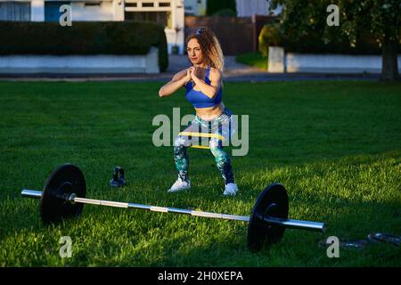 Persönlicher Fitnesstrainer, der Stretching-Übungen durchführt und Gewichte im Freien hebt. Stockfoto