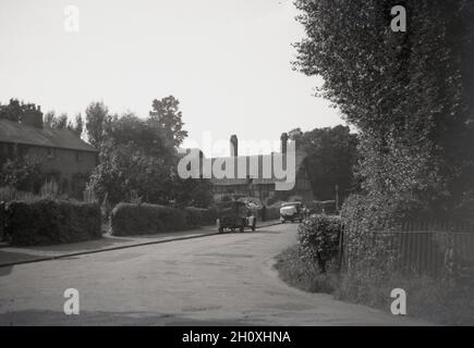 1940er Jahre, historisches Bild mit Autos aus dieser Zeit, die auf einer ruhigen Landstraße neben Anne Hathaways Hütte in Stratford-upon-Avon, England, Großbritannien, geparkt wurden. Dieses reetgedeckte Farmhaus - in der Ferne gesehen - war das Kinderhaus der Ehefrau des berühmten englischen Dramatikers William Shakespare und befindet sich in Shottery, etwas außerhalb von Stratford. Es war 400 Jahre lang das Zuhause der Familie Hathaway, bis 1911. Stockfoto