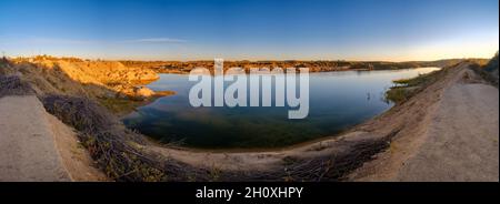 Full nahtloses Panorama 180-Winkel-Ansicht in der Nähe von Steinbruch mit Wasser für die Sandgewinnung Bergbau in der Abendsonne überschwemmt. Die Landschaft des verlassenen Steinbruchs sieht aus wie der Mars. Stockfoto