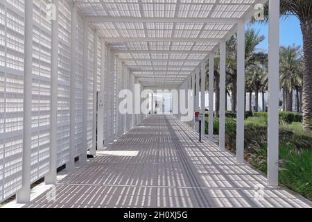 Schwindende futuristische Perspektive des Eintritts in den weißen Spaliergang zum berühmten Louvre-Kunstmuseum. Abu Dhabi, VAE Stockfoto