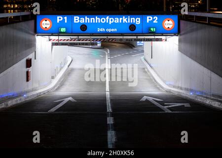 Eingang zum Tiefgaragenparkplatz mit deutschen Inschriften in Luzern. Nachtsicht, beleuchtet durch Lichter. Straßenschilder auf dem Boden. Stockfoto