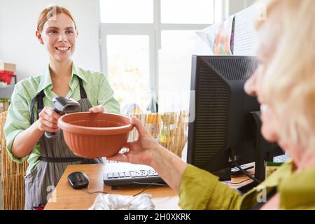 Kunde bei Zahlung an der Kasse des Gartencenters mit Kassierer beim Scannen Stockfoto