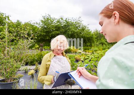 Zwei Gärtnerinnen mit Checkliste machen Inventar oder schreiben Aufträge auf Stockfoto