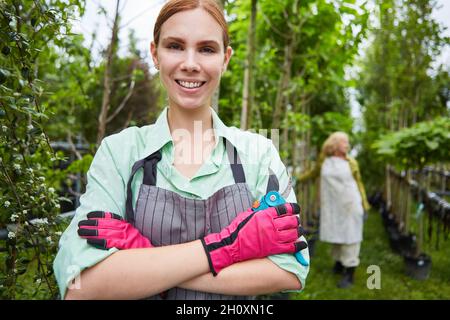 Junge Frau als stolze Gärtnerin mit Gartenscheren in der Gärtnerei Stockfoto