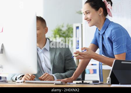 Lächelnder Mann und Frau diskutieren am Arbeitstisch über Geschäftsprozesse Stockfoto