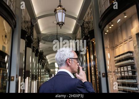 Mann, der eine Zigarre raucht, am Eingang der Piccadilly Arcade, London, England, Großbritannien Stockfoto