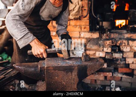 Ein Schmied schmiedet von Hand in einer Schmiede auf einem Stahlanvil - ein altes Handwerk Stockfoto