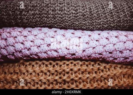 Drei bequeme Strickpullover liegen in einer Reihe. Herbst Winter Kleidung Konzept. Warmes Material. Orange rosa braune Farben Stockfoto