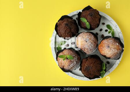Tablett mit Schokoladen-Muffins auf gelbem Hintergrund. Stockfoto