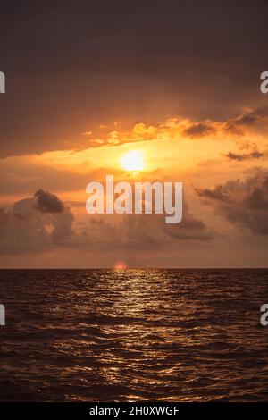 Hell feurig bunten Meer Sonnenuntergang - wolkiger Himmel und Wellen auf dem Wasser - vertikal schöne Landschaft bei Sonnenuntergang in gelb-roten und orangen Farben Stockfoto