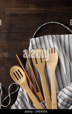Schürze mit Küchengerät auf Holzhintergrund. Stockfoto