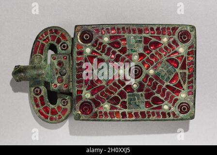 Gürtelschnalle, c. 525-560. Westgotik, Spanien, Migrationsperiode, 6. Jahrhundert. Bronze mit Granaten, Glas, Perlmutt, Goldfolie, Vergoldungsspuren; Bronze und Glas; insgesamt: 7.1 x 2.7 cm (2 13/16 x 1 1/16 Zoll). Die Kunst der Europäischen Migrationsperiode (3.-7. Jahrhundert n. Chr.) ist fast ausschließlich eine Kunst der persönlichen Verzierung – eine tragbare Kunst, die Männern und Frauen zu ihren Gräbern folgte. Gürtelschnallen mit großen rechteckigen Befestigungsplatten wurden auf Friedhofs auf der iberischen Halbinsel entdeckt, die jetzt von Spanien und Portugal besetzt ist, und zwar aus der Zeit der westgotischen Besatzung (etwa 412–711 n. Chr.). Stockfoto