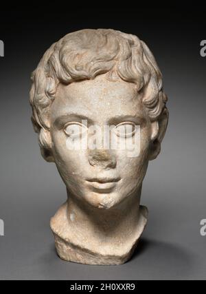 Portrait Kopf einer Jugend, AD 1-100. Ägypten, Alexandria, römisch, 1. Jahrhundert n. Chr. Marmor; insgesamt 29.5 cm (11 5/8 Zoll). Mehrere ungewöhnliche Merkmale dieses Kopfes deuten darauf hin, dass seine Schnitzerei in der Antike nie beendet wurde. Dazu gehören unfertige Haare um die Ohren, kleine Beulen, die in den Haaren in der Nähe der Vorder- und Oberseite des Kopfes verbleiben, und das Fehlen einer fein polierten Oberfläche. Obwohl man sagt, dass er in Ägypten gefunden wurde, ist der Kopf aus dolomitischem Marmor geschnitzt, der vermutlich aus der Region Saliari der nordgriechischen Insel Thasos stammt. Stockfoto