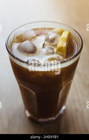 Eiskaffee in einem Glas mit Eis und Zitrone - ein Sommergetränk für Lebendigkeit Stockfoto