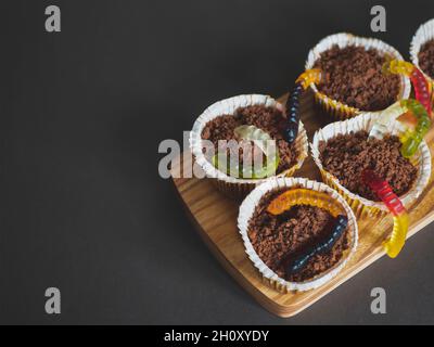 Halloween Schokolade Cupcakes mit Gelee Würmer aus dem Boden kommen. Essen für Kinder Party. Urlaub lustige Snacks Stockfoto