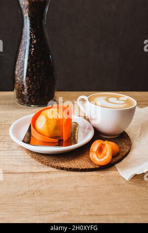 Süßes, wunderschönes handgebasteltes Aprikosendessert in einem Café mit einer Tasse Kaffee Stockfoto