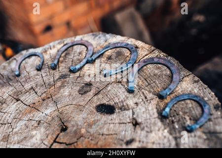 Handgeschmiedete Hufeisen auf einem Baumstumpf - das Handwerk eines altmodischen Schmieds Stockfoto