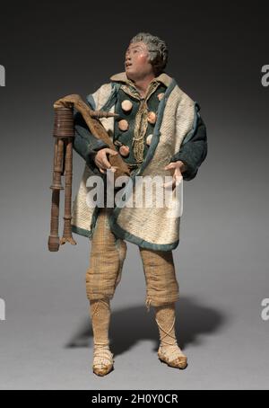 Abbildung aus einer Crèche: Piper, 1780-1830. Italien, Neapel, Ende des 18.-frühen 19. Jahrhunderts. Lackiertes Holz und Terrakotta mit verschiedenen Textilien; insgesamt 27.3 cm (10 3/4 in.). Die Praxis, Szenen der Geburt Christi für die Heimat zu schaffen, stammt aus dem frühen 17. Jahrhundert in Italien, wo die Menschen begannen, puppenartige Figuren von etwa einem Fuß oder weniger Höhe aufzurichten. Besonders beliebt war der Brauch in Neapel um 1800, wo crèche Szenen (crèche bedeutet Wiege oder Krippe) viele Figuren umfassten, deren Köpfe und Hände aus bemaltem Terrakotta, Stoffkörper und Kleidung, die aus zeitgenössischen lokalen Kostümen adaptiert wurde Stockfoto