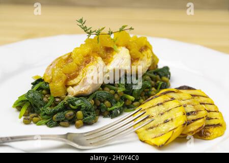 Nahaufnahme von gekochten Erbsen, Spinat und Huhn mit gegrillten Kartoffeln Stockfoto