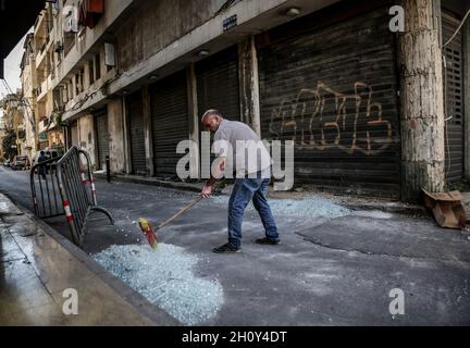 Beirut, Libanon. Oktober 2021. Ein libanesischer Mann fegt zerbrochenes Glas aus einer Gasse im Tayouneh-Gebiet, nachdem gestern die tödlichen gewalttätigen Zusammenstöße zwischen muslimischen schiitischen Militanten der pro-iranischen Hisbollah und Gegnern stattgefunden haben. Bei einem Protest gegen einen Richter, der die massive Explosion im Hafen der Stadt im vergangenen Jahr untersucht, wurden heute in Beirut mindestens sechs Menschen getötet und 32 weitere verletzt. Quelle: Marwan Naamani/dpa/Alamy Live News Stockfoto