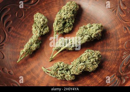 Cannabisknospen in brauner Tonschale, flacher Lat, Draufsicht. Marihuana-Blüten aus nächster Nähe. Hanf Erholung, Canna Küche, Legalisierungskonzept. Stockfoto