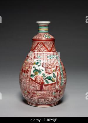 Tee-Sake-Flasche in Whiskform, 1660er bis Anfang 1670er Jahre. Japan, Edo-Zeit (1615-1868). Porzellan mit Emaille-Glasur (Hizen-Geschirr, Kakiemon-Typ, Ko-Kutani-Stil); insgesamt: 25.4 x 14.7 x 14.7 cm (10 x 5 13/16 x 5 13/16 Zoll). Diese Sake-Flasche ähnelt einem Schneebesen, der bei der Zubereitung von pulverförmiges grünem Tee verwendet wird, wobei der Griff oben und der Bürstenkörper unten aufflackert. Sein kühnes Design wird durch Bilder von Chrysanthemen und Granatäpfeln in Paneelen auf einem Boden aus roten Schraffuren mit dreifarbigen Wolken verankert. Zusätzliche Muster aus Wirbeln, Streifen, Blumen und anderen Formen machen das Stück zum Blickfang Stockfoto