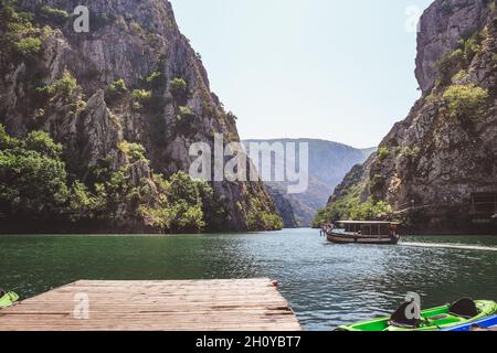 Blick auf den See in der Matka-Schlucht in der Nähe von Skopje, Republik Nordmakedonien im Sommer. Boot auf dem See, Kajaks in der Nähe des Docks Stockfoto