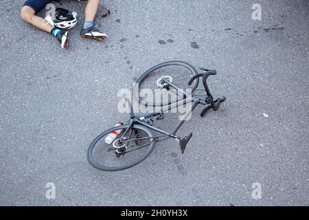 Fahrradunfall auf der Straße. Szene eines Radfahrers und eines Fahrrads auf dem Asphalt, nachdem er von einem Fahrzeug getroffen wurde Stockfoto