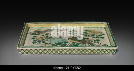 Tablett mit Phönixen in Landschaft, 1662-1722. China, Provinz Jiangxi, Brennöfen von Jingdezhen, Qing-Dynastie (1644-1911), Kangxi-Herrschaft (1662-1722). Porzellan mit eingeschnitzter und sancai (3-farbiger) Emaille-Verzierung; insgesamt 14 cm (5 1/2 in.). Stockfoto