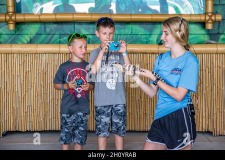 Der Tierführer zeigt zwei jungen Gästen im Ocean Adventures Marine Park in Gulfport, Mississippi, ein Baby-Alligator Stockfoto