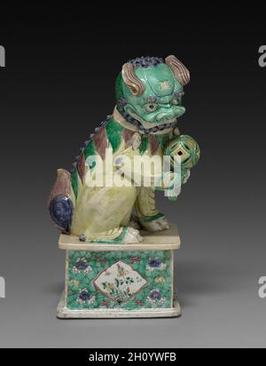 Lion, 1662-1722. China, Qing-Dynastie (1644-1911), Kangxi-Herrschaft (1661-1722). Porzellan mit Emaille-Überglasur; insgesamt: 45.2 cm (17 13/16 in.). Dieser Porzellanlöwe ist ein Paar mit 1930.642. Dieser Löwe, der einen Ball hält, gilt als männlich, während das pflegende Weibchen mit einem Jungen dargestellt wird. Schutzlöwen wurden traditionell vor Gebäuden platziert, um vor schädlichen geistigen oder menschlichen Kräften zu schützen. Stockfoto