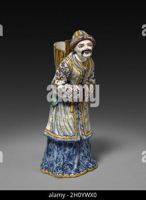 Abbildung, 1745-1750. Strasbourg Factory (Französisch). Fayence; insgesamt: 28.9 x 13.7 x 12.7 cm (11 3/8 x 5 3/8 x 5 Zoll). In der Mitte des 18. Jahrhunderts war die Familie Hannong mehrere Jahrzehnte lang Eigentümer einer der besten und einflussreichsten französischen Fayence-Fabriken in Straßburg. Hier trafen sich deutsche und französische Keramikstile und -Techniken und wurden miteinander verschmolzen. Diese Figuren wurden von einem Paar aus Chantilly-Porzellan kopiert, das wiederum auf einem Meissen-Prototyp basierte. Stockfoto