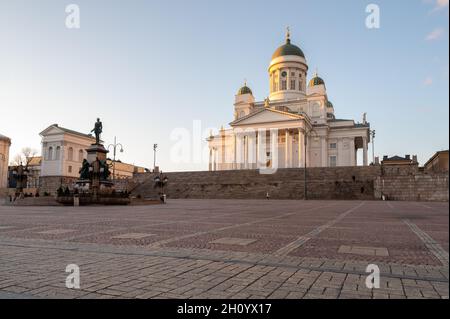 Helsinki / Finnland - 14. MÄRZ 2020: Kathedrale von Helsinki auf einem Hügel bei Sonnenuntergang. Senatsplatz und Alexander-Statue im Vordergrund. Stockfoto