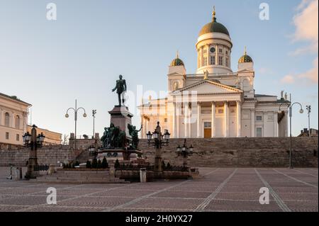 Helsinki / Finnland - 14. MÄRZ 2020: Kathedrale von Helsinki auf einem Hügel bei Sonnenuntergang. Senatsplatz und Alexander-Statue im Vordergrund. Stockfoto