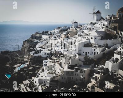 Panoramablick auf das Dorf Oia mit traditioneller weißer Architektur und Windmühlen auf der Insel Santorini in der Ägäis, Reisehintergrund, Santorini, Thera Stockfoto