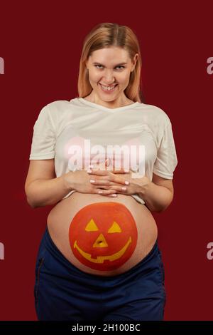 Junge schwangere Frau mit Kürbis Halloween gemalt auf dem Bauch Stockfoto