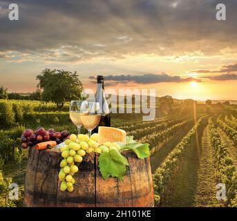 Farbenprächtiger Sonnenuntergang über der Wachau mit einer Flasche Wein auf dem Fass gegen goldene Weingärten in Österreich Stockfoto