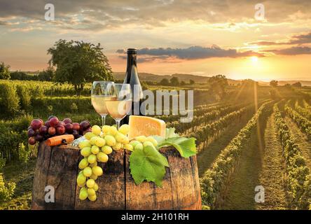 Sonnenuntergang über der Wachau mit einer Flasche Wein auf dem Fass gegen goldene Weingärten in Österreich Stockfoto