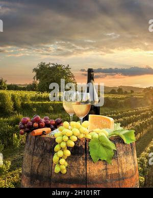 Farbenprächtiger Sonnenuntergang über der Wachau mit einer Flasche Wein auf dem Fass gegen goldene Weingärten in Österreich Stockfoto