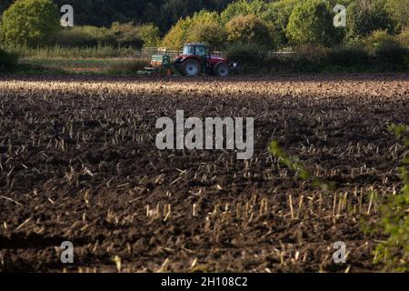 Der Traktor schoss an einem sonnigen Tag auf dem gepflügten Feld von der Seite Stockfoto