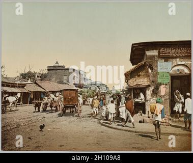 Indien. Kalkutta. Upper Chitpore Road (A), nach Foto von Dr. Kurt Boeck, c. 1890-1910. Photoglob Co. (Zürich, aktive c. 1890-1910). Photochrom; Papier: 20.6 x 26.2 cm (8 1/8 x 10 5/16 Zoll). Diese geschäftige Straßenecke gibt uns einen Einblick in den Alltag im Indien der Wende des 20. Jahrhunderts. Im Gegensatz zu den meisten Genrefotografien des kolonialen Indiens aus der Mitte des 19. Jahrhunderts, die posiert oder inszeniert wurden, gehen hier Menschen ihre Geschäfte, ohne zu wissen, dass sie fotografiert werden. Die Farbszene wurde mit einem Schwarz-Weiß-Negativ von Dr. Kurt Boeck gemacht, einem deutschen Schauspieler und Bergsteiger, der zum TR wurde Stockfoto