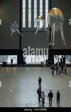 London, Großbritannien. Oktober 2021. Die Besucher sehen schwebende Kunstflugkörper, die Anicka Yis neues Luftwerk „in Love With The World“ bilden, in der Turbine Hall of Tate Modern für die Hyundai-Kommission 2021. Die Installation besteht aus Maschinen, die als Kunstflugkörper bezeichnet werden, basierend auf Lebensformen des Ozeans und Pilzen, die in der Luft schweben, und stellt eine Neueinbildung dar, wie künstliche Intelligenz und neue Maschinen die Welt bewohnen könnten. Die Arbeit kann bis zum 16. Januar 2022 erlebt werden. Kredit: Stephen Chung/Alamy Live Nachrichten Stockfoto