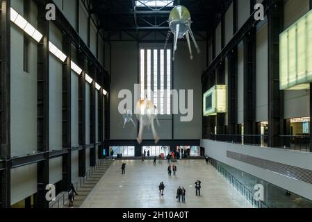 London, Großbritannien. Oktober 2021. Die Besucher sehen schwebende Kunstflugkörper, die Anicka Yis neues Luftwerk „in Love With The World“ bilden, in der Turbine Hall of Tate Modern für die Hyundai-Kommission 2021. Die Installation besteht aus Maschinen, die als Kunstflugkörper bezeichnet werden, basierend auf Lebensformen des Ozeans und Pilzen, die in der Luft schweben, und stellt eine Neueinbildung dar, wie künstliche Intelligenz und neue Maschinen die Welt bewohnen könnten. Die Arbeit kann bis zum 16. Januar 2022 erlebt werden. (Langzeitbelichtung). Kredit: Stephen Chung/Alamy Live Nachrichten Stockfoto