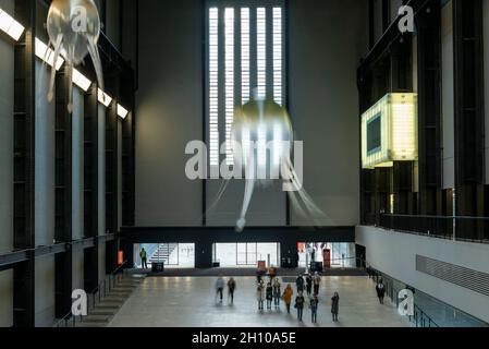 London, Großbritannien. Oktober 2021. Die Besucher sehen schwebende Kunstflugkörper, die Anicka Yis neues Luftwerk „in Love With The World“ bilden, in der Turbine Hall of Tate Modern für die Hyundai-Kommission 2021. Die Installation besteht aus Maschinen, die als Kunstflugkörper bezeichnet werden, basierend auf Lebensformen des Ozeans und Pilzen, die in der Luft schweben, und stellt eine Neueinbildung dar, wie künstliche Intelligenz und neue Maschinen die Welt bewohnen könnten. Die Arbeit kann bis zum 16. Januar 2022 erlebt werden. (Langzeitbelichtung). Kredit: Stephen Chung/Alamy Live Nachrichten Stockfoto