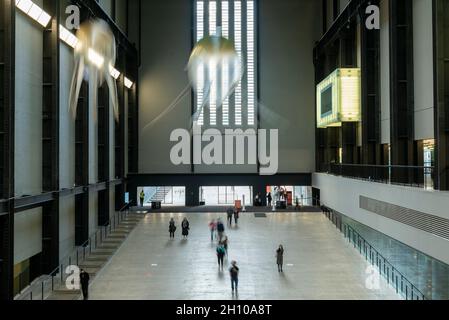 London, Großbritannien. Oktober 2021. Die Besucher sehen schwebende Kunstflugkörper, die Anicka Yis neues Luftwerk „in Love With The World“ bilden, in der Turbine Hall of Tate Modern für die Hyundai-Kommission 2021. Die Installation besteht aus Maschinen, die als Kunstflugkörper bezeichnet werden, basierend auf Lebensformen des Ozeans und Pilzen, die in der Luft schweben, und stellt eine Neueinbildung dar, wie künstliche Intelligenz und neue Maschinen die Welt bewohnen könnten. Die Arbeit kann bis zum 16. Januar 2022 erlebt werden. Kredit: Stephen Chung/Alamy Live Nachrichten Stockfoto