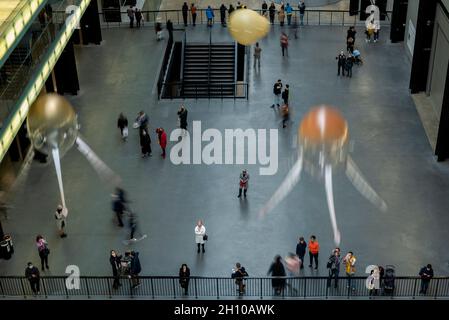 London, Großbritannien. 15. Oktober 2021. Die Besucher sehen schwebende Kunstflugkörper, die Anicka Yis neues Luftwerk „in Love With The World“ bilden, in der Turbine Hall of Tate Modern für die Hyundai-Kommission 2021. Die Installation besteht aus Maschinen, die als Kunstflugkörper bezeichnet werden, basierend auf Lebensformen des Ozeans und Pilzen, die in der Luft schweben, und stellt eine Neueinbildung dar, wie künstliche Intelligenz und neue Maschinen die Welt bewohnen könnten. Die Arbeit kann bis zum 16. Januar 2022 erlebt werden. (Langzeitbelichtung). Kredit: Stephen Chung / Alamy Live Nachrichten Stockfoto